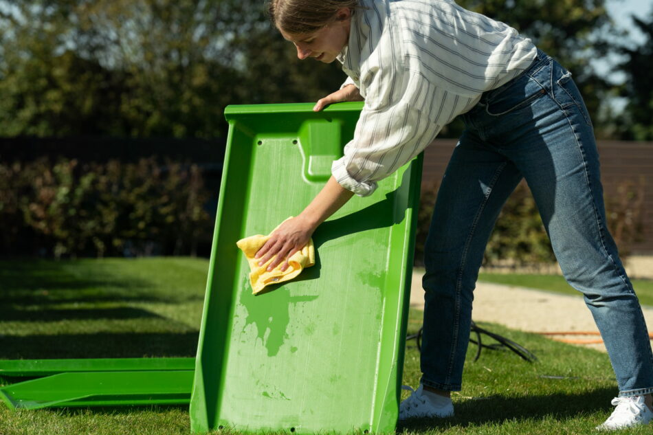 femme qui essuie un bac à déjections Eglu avec un chiffon