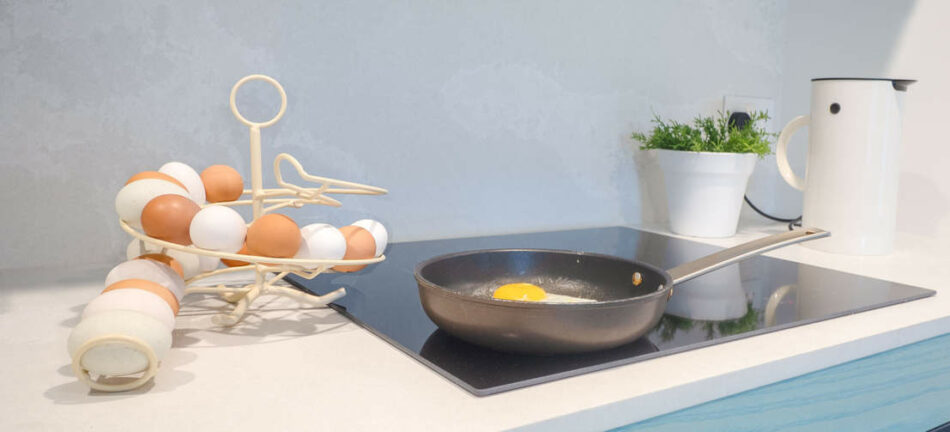 Le présentoir à œufs d’Omlet à côté d’un œuf en train de cuire