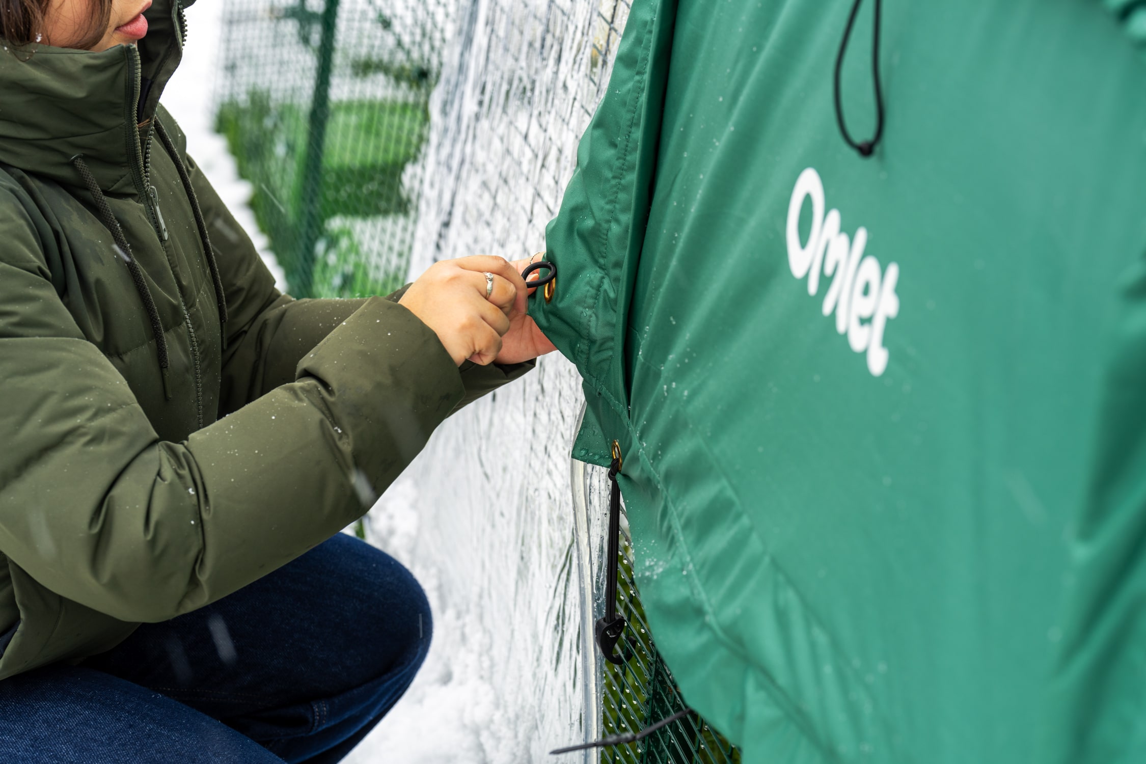 Femme qui fixe une couverture thermique pour températures extrêmes à un poulailler Eglu-Pro