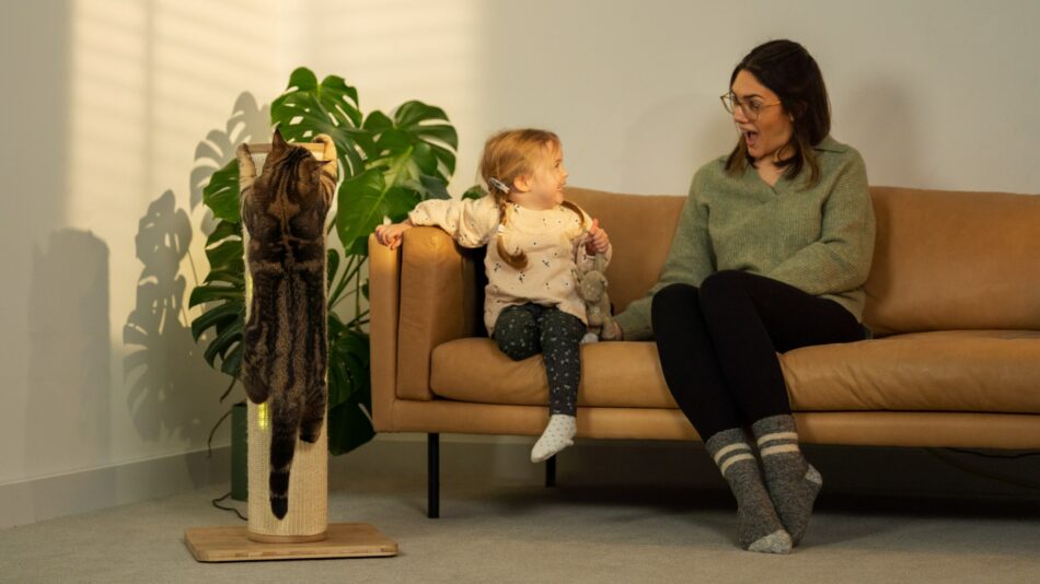 Une femme et une fille sur le canapé avec un chat qui utilise le griffoir Switch d’Omlet  