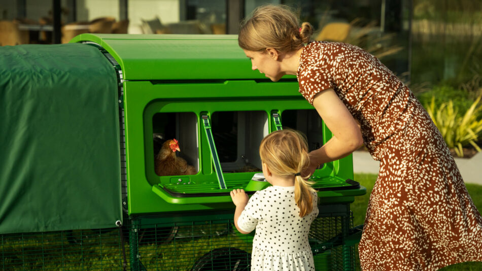 Femme et enfant qui regardent une poule dans le nichoir du poulailler Eglu Pro