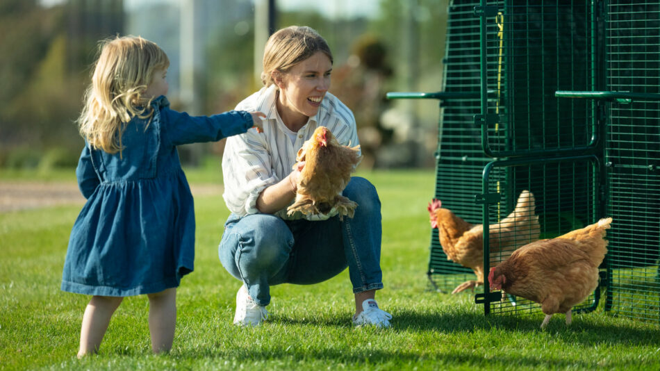 Comportement des poules — une femme et une fille avec des poules à l’extérieur du poulailler Eglu Pro