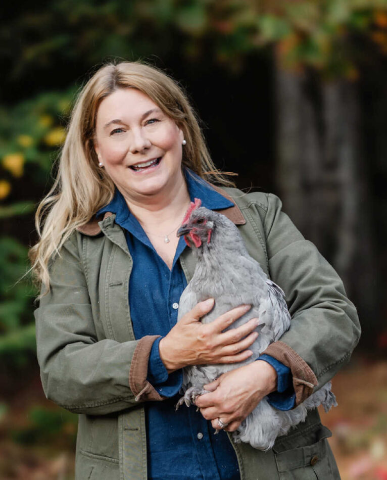 Femme qui sourit et tient sa poule dans les mains