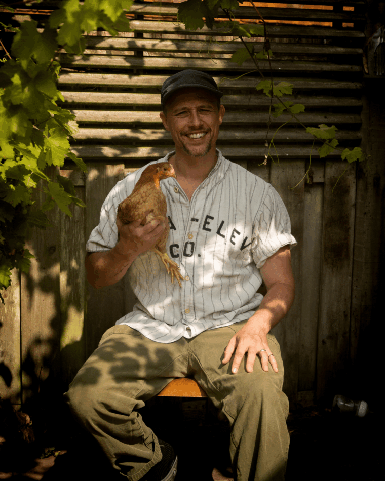 JP Cooper assis avec une poule dans les bras